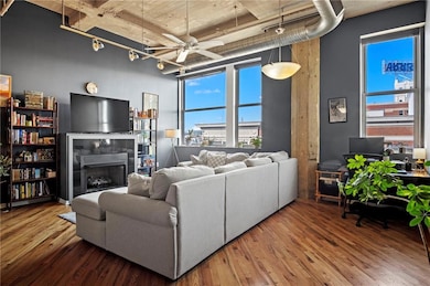 Living area with rail lighting, a towering ceiling, a tiled fireplace, and wood finished floors