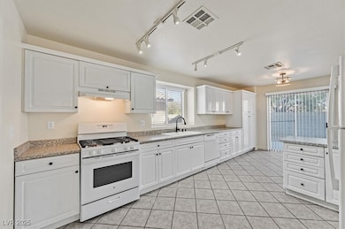 Kitchen with white appliances, white cabinetry, light tile patterned floors, and rail lighting