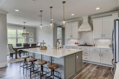 Kitchen with high end light and plumbing fixtures, tile back splash, cabinet vent hood, and quartz countertops
