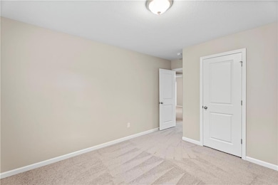 Unfurnished bedroom featuring light colored carpet and baseboards