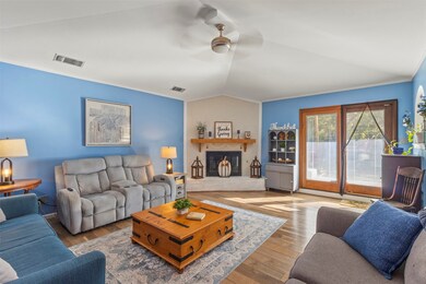 Living area featuring crown molding, wood finished floors, vaulted ceiling, a ceiling fan, and a fireplace