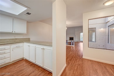 Kitchen with light wood finished floors, white cab
