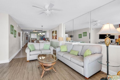 Living room featuring a ceiling fan, wood finished floors, a chandelier, and a textured ceiling