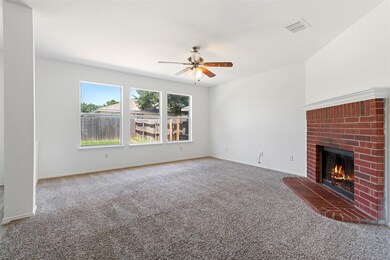 Carpeted living room with fireplace, ceiling fan, and view of back yard.