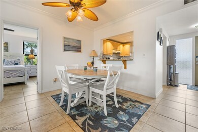 Tiled dining space with ceiling fan and crown mold