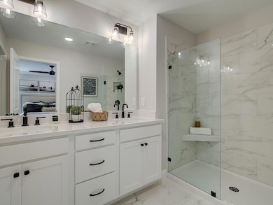Ensuite bathroom featuring a marble finish shower, light marble finish flooring, and double vanity