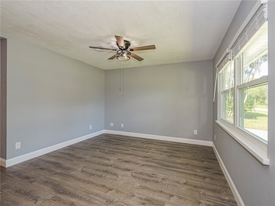 Empty room featuring a textured ceiling, dark wood-style floors, and ceiling fan