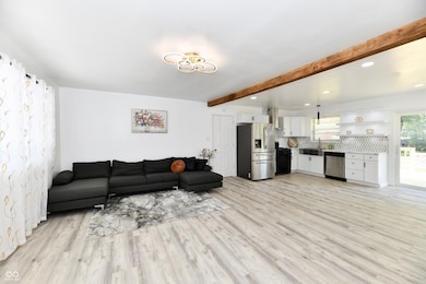 living area with beamed ceiling, light wood-style flooring, and recessed lighting
