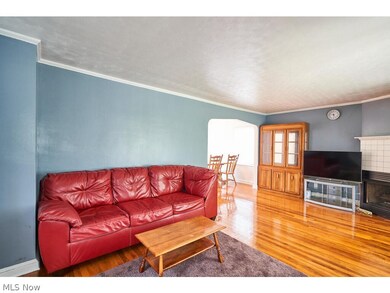 Living room with crown molding, a tiled fireplace, and hardwood / wood-style floors