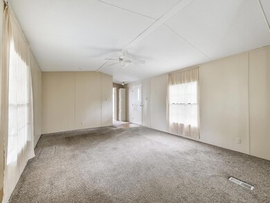 Large family area features a ceiling fan and updated carpet flooring.