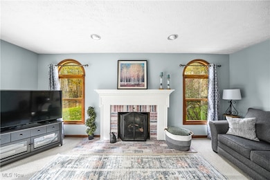 Living area with carpet flooring, a brick fireplace, a textured ceiling, and recessed lighting