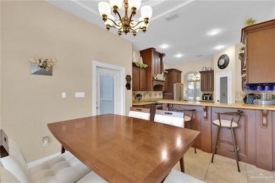 Dining space with a chandelier, light tile patterned floors, and baseboards