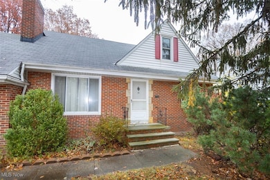 View of front of house featuring a chimney, brick siding, and roof with shingles
