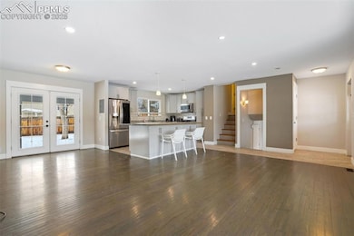 Kitchen featuring a kitchen island, appliances with stainless steel finishes, pendant lighting, white cabinetry, and a kitchen bar