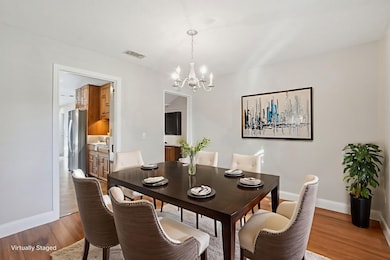 STAGED PHOTO - Dining room featuring wood finished floors and a chandelier