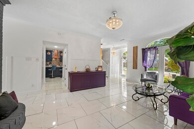 Living area featuring a desk, a chandelier, stairway, light marble finish floors, and crown molding