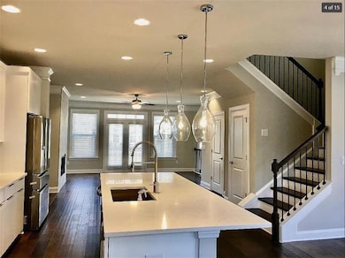 Kitchen featuring dark wood-style floors, ceiling fan, a center island with sink, white cabinetry, and freestanding refrigerator