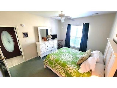 Carpeted bedroom featuring ceiling fan and baseboa