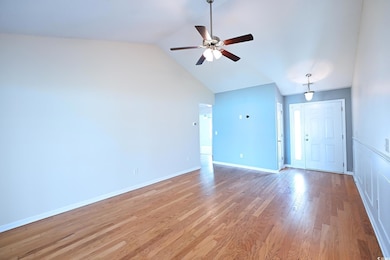 Unfurnished living room featuring wood finished floors, lofted ceiling, and a ceiling fan