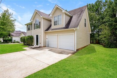 Traditional-style home with an attached garage, driveway, a front yard, and a shingled roof