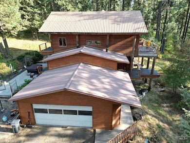Rustic home featuring a metal roof, a garage, a forest view, and a wooden deck