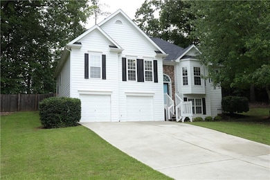 Raised ranch featuring a garage and concrete driveway