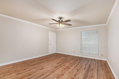 Empty room with crown molding, light wood-style flooring, and a ceiling fan