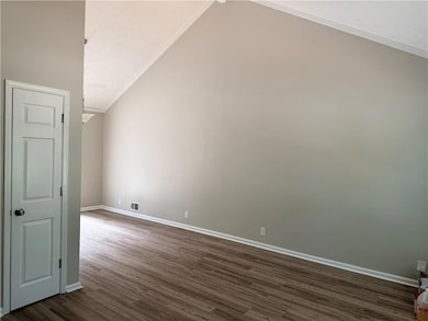Additional living space featuring dark wood finished floors and vaulted ceiling