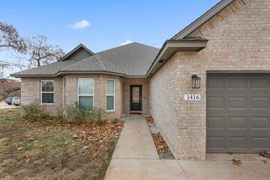 Doorway to property with roof with shingles, brick siding, and an attached garage