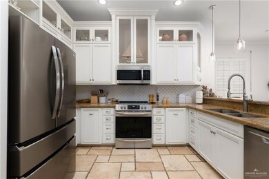 Kitchen featuring appliances with stainless steel finishes, a sink, crown molding, tasteful backsplash, and white cabinetry