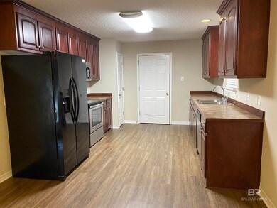 Kitchen with a textured ceiling, appliances with stainless steel finishes, light hardwood / wood-style floors, sink, and dark brown cabinetry