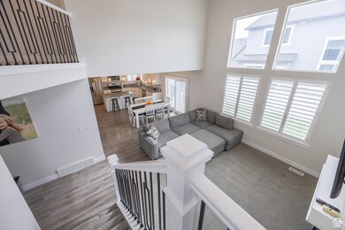 Living area featuring a towering ceiling, a chandelier, healthy amount of natural light, and wood finished floors