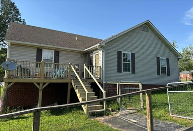 Back of house with a deck, fence, stairway, and a 