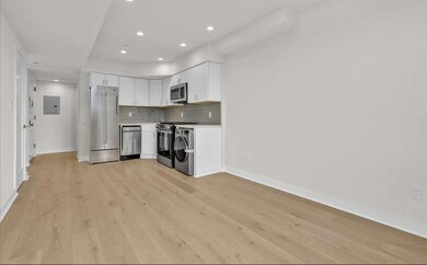 Kitchen featuring white cabinetry, backsplash, electric panel, appliances with stainless steel finishes, and light wood-type flooring