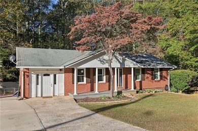Single story home featuring a porch, brick siding, a front yard, driveway, and a shingled roof