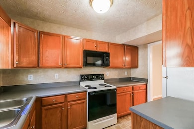 Kitchen featuring a sink, brown cabinets, range with electric stovetop, and black microwave