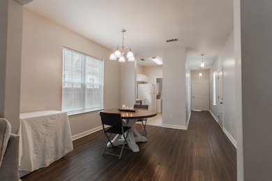 Dining area with a chandelier and dark hardwood / 