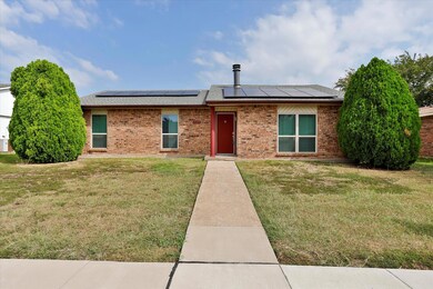 View of front of home with a front yard and solar 