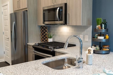 Kitchen featuring appliances with stainless steel finishes, decorative backsplash, and modern cabinets