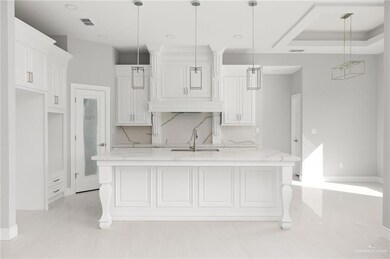 Kitchen with visible vents, white cabinets, a sink, backsplash, and light stone counters
