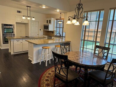 Breakfast area with an inviting chandelier and dark hardwood floors offer open concept dining