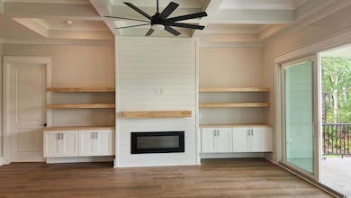Unfurnished living room with coffered ceiling, ornamental molding, ceiling fan, wood finished floors, and a fireplace