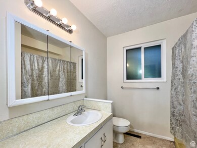 Bathroom with vanity, a textured ceiling, curtained shower, and tile patterned flooring