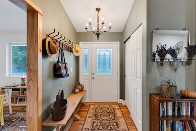 Mudroom featuring wood finished floors, plenty of natural light, a chandelier, and a textured wall