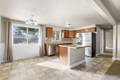 Kitchen with brown cabinets, stainless steel appliances, light countertops, decorative light fixtures, and a chandelier