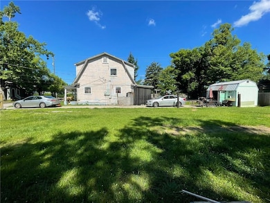 View of side of home with a yard and a gambrel roof