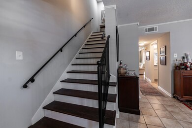 Stairs featuring ornamental molding, a textured ceiling, and tile patterned floors