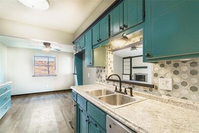 Kitchen featuring tasteful backsplash, ceiling fan, sink, a textured ceiling, and a stone fireplace