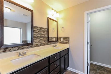 Bathroom featuring double vanity and tasteful backsplash