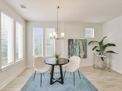 Dining room with healthy amount of natural light, light wood-style flooring, and a chandelier